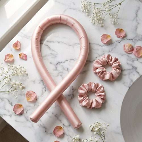 CurlBloom blush pink silk heatless curling wand headband and matching scrunchies flat-lay on white marble with rose petals
